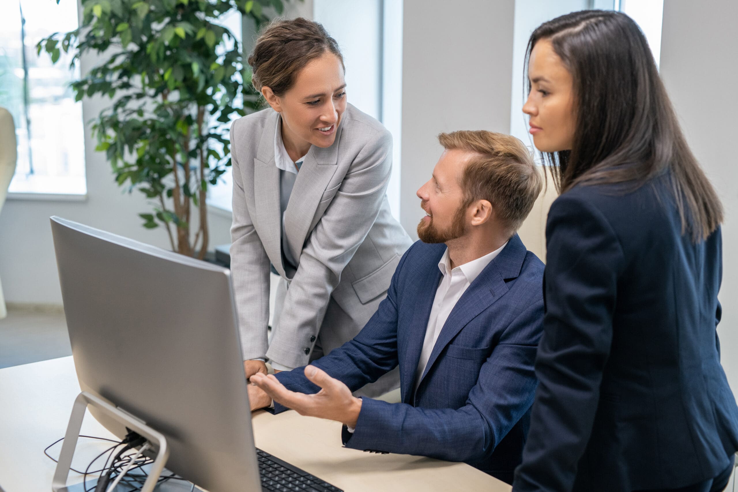 Young successful businesspeople in formalwear interacting in front of computer